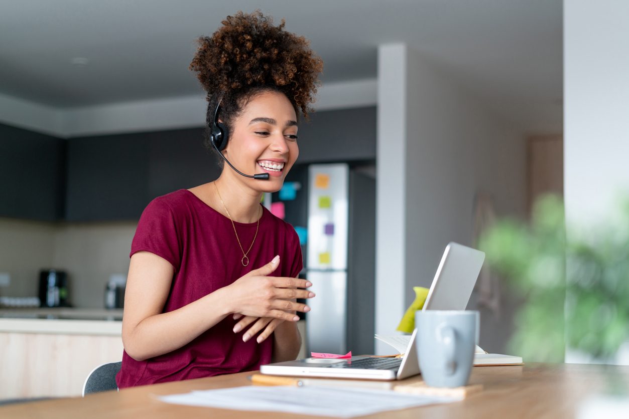 Happy African American woman working from home doing customer retention as a customer service representative and using a headset