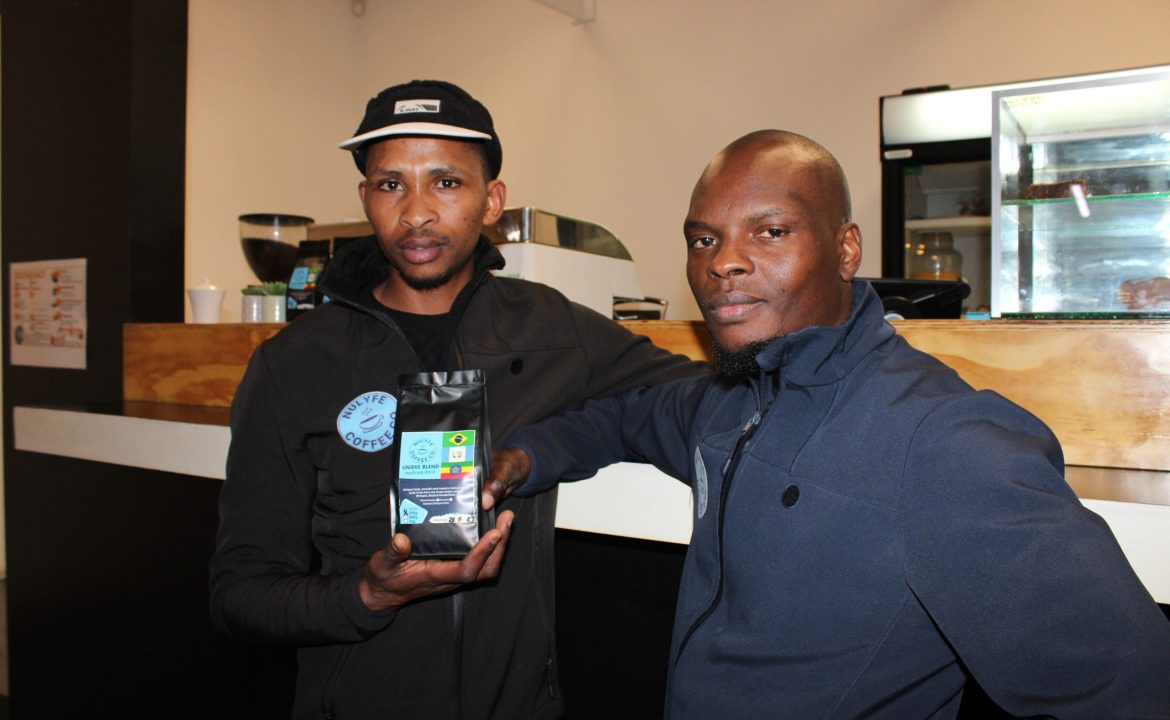 Photo of two Sam and Charles holding a bag of coffee beans