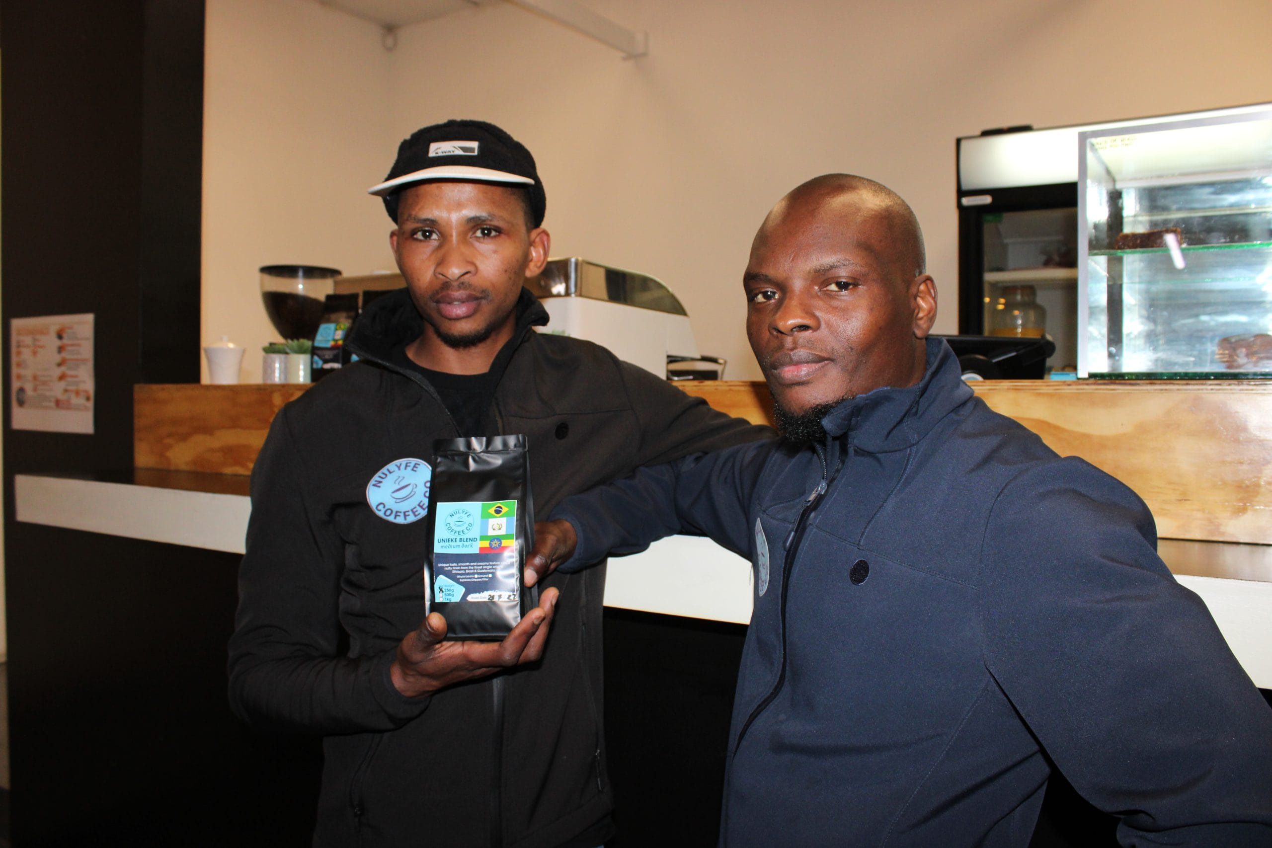 Photo of two Sam and Charles holding a bag of coffee beans