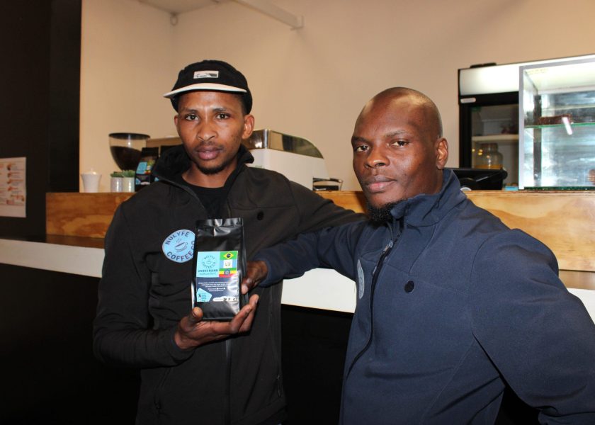 Photo of two Sam and Charles holding a bag of coffee beans