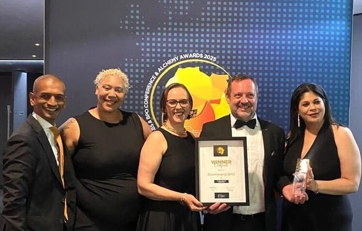 Boomerang Team of 5 standing with top BPO Operator Award in front of a sign with event name