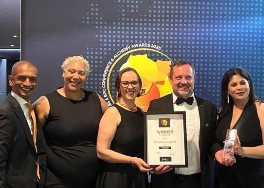 Boomerang Team of 5 standing with top BPO Operator Award in front of a sign with event name